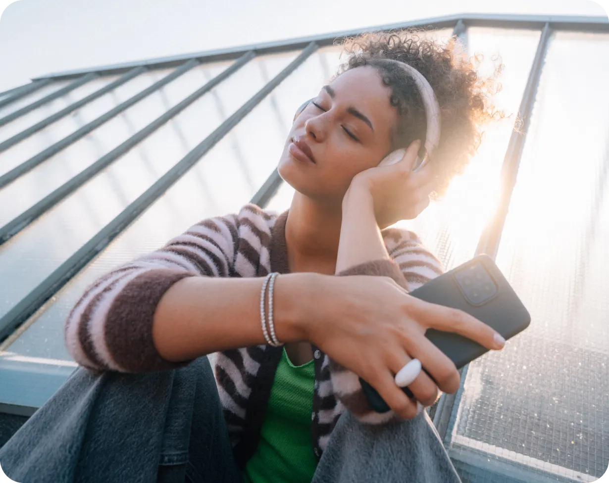 Junge Frau streamt Musik in der Sonne
